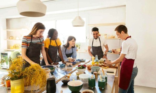 Spanish Cooking Classes in Barcelona.Tourists and chef in a cooking workshop preparing food.